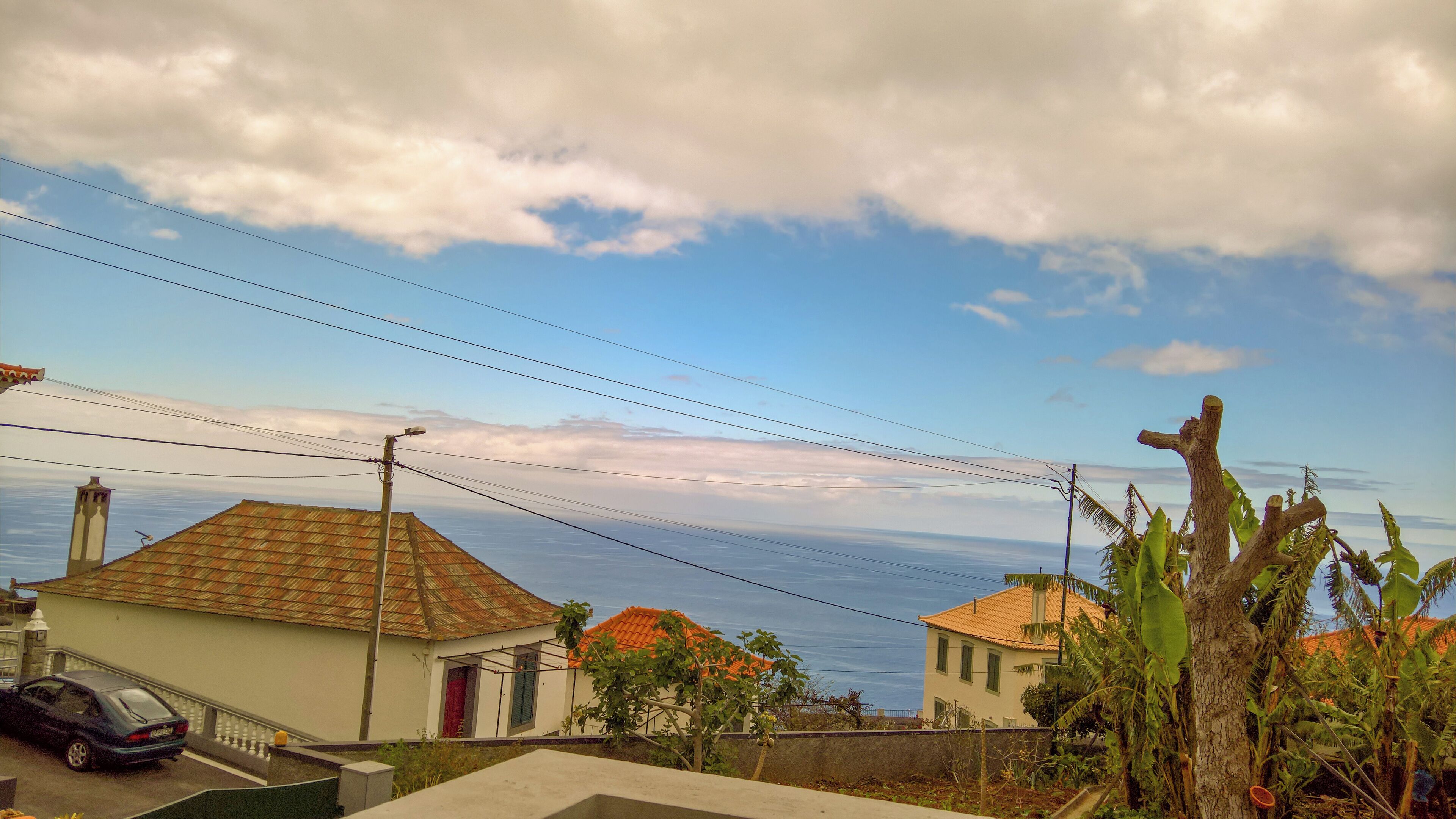Ein Küstenwohngebiet mit Häusern, einem Auto und Blick auf das Meer.