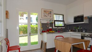 Una cocina con mesa, sillas y vistas a través del ventanal.