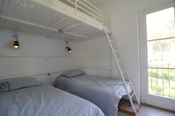 A room with bunk beds, a ladder, and two wall-mounted lights.