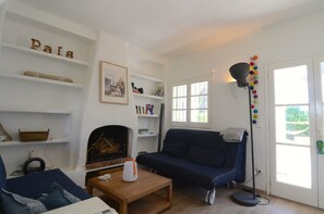 Een woonkamer met een open haard, een bank, een bijzettafeltje en een boekenkast.