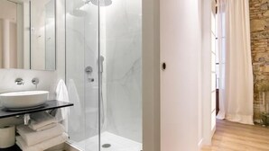 A modern bathroom with a glass-enclosed shower, a white sink, and a mirror. - Mid-term apartment 13 (Barcelona)