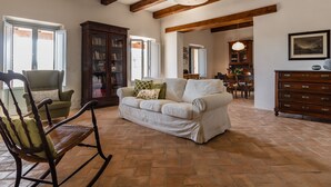Un salón amplio con una mecedora de madera, un sofá blanco y un mueble de madera.