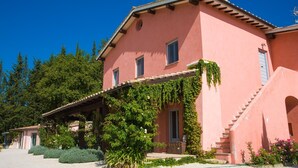 Una villa rosa con un porche cubierto y una escalera que lleva a la entrada.
