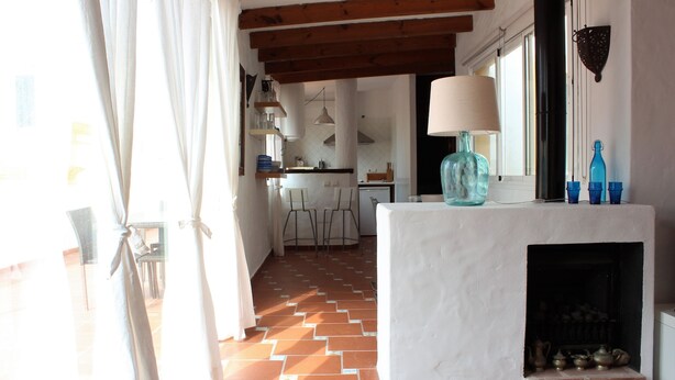 A kitchen with a tiled floor, a fireplace, and a window with curtains. - Attic apartment in old town Tarifa (Tarifa)