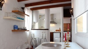 A modern kitchen with white cabinets, a large white table, and a dining area with clear chairs. - Attic apartment in old town Tarifa (Tarifa)