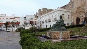 A statue in a public square with a fountain, surrounded by greenery and historic buildings. - Attic apartment in old town Tarifa (Tarifa)