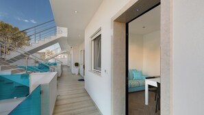A modern interior with a staircase leading to an upper level, a dining area with a table and chairs, and a view of the outdoors. - Absolute Suite Apartments - Bilo PT (Porto Cesareo)