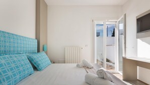 A bedroom with a bed, a TV, and a view of the outdoors. - Absolute Suite Apartments - Bilo PT (Porto Cesareo)