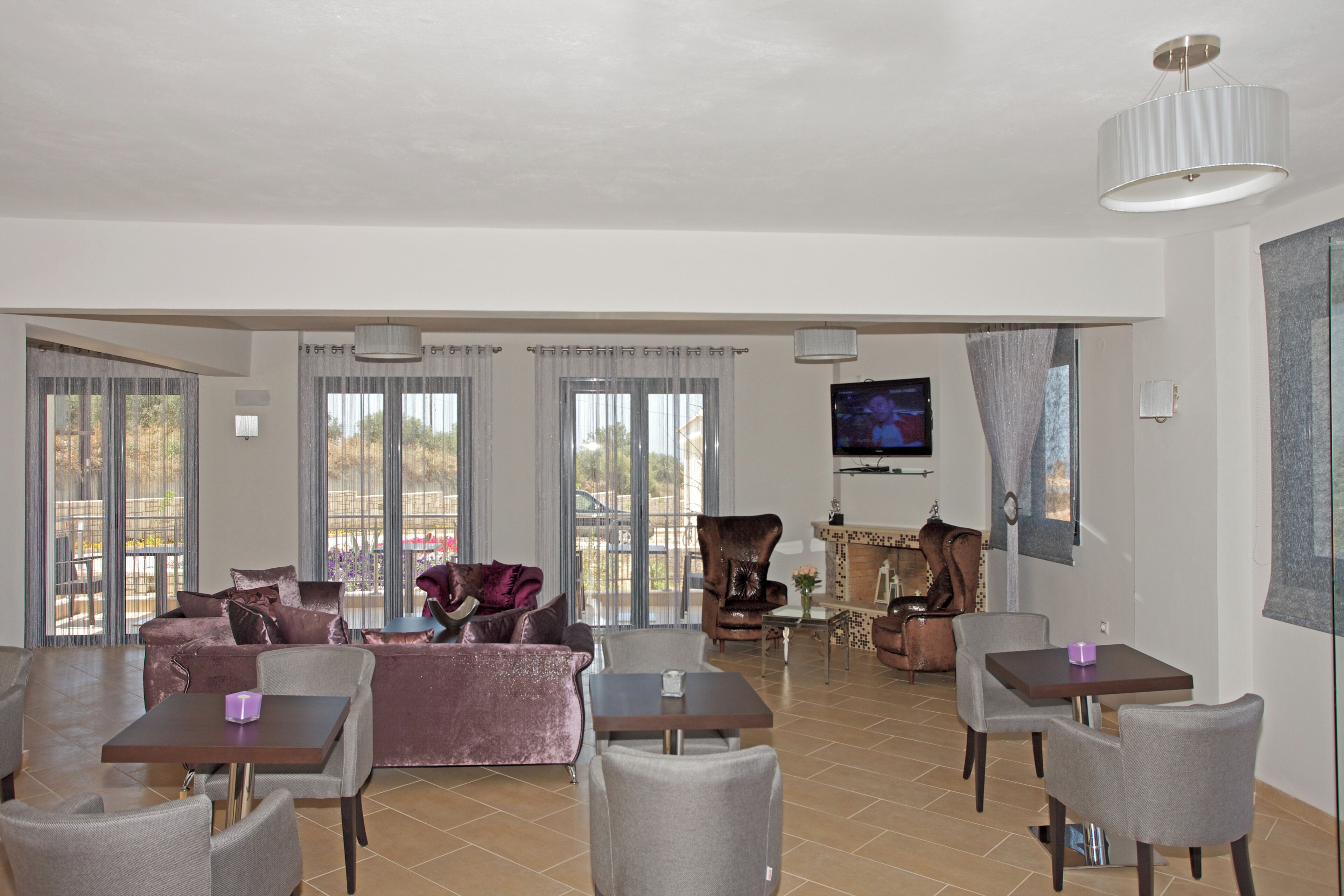 A spacious living area with a sofa, chairs, a dining table, and a TV.