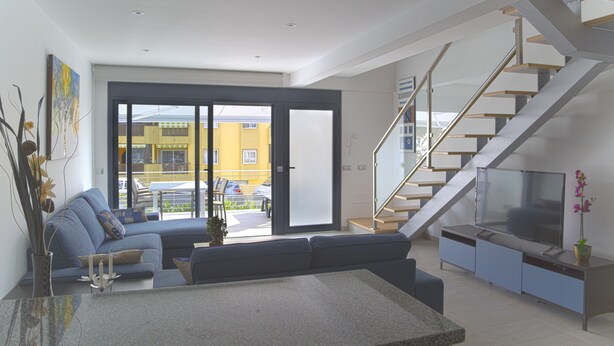 A modern living room with a sofa, a coffee table, and a TV on a stand. - Idaira II new spacious apartment with private garage and beach walking distance (Los Cristianos)