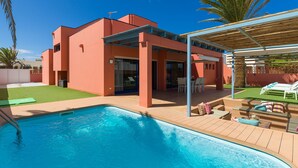 A modern house with a swimming pool, outdoor seating, and a covered patio area.