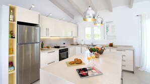 Eine moderne Küche mit weißen Schränken, einem Edelstahl-Kühlschrank und einer Frühstücksecke auf der Kochinsel.