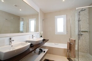 A modern bathroom with two sinks, a bathtub, and a glass-enclosed shower. - Villa Alba (Pollensa)