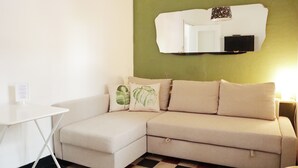 A room with a beige sectional sofa, a small white table, and a checkered floor.