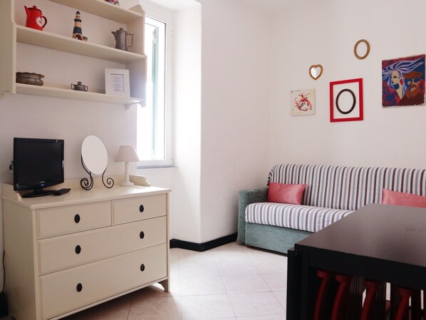 Una habitación con televisión sobre un aparador, un sofá a rayas y una mesita pequeña.