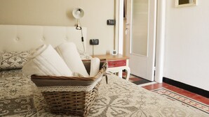 A bedroom with a bed, a bedside table, a lamp, a mirror, and a door.