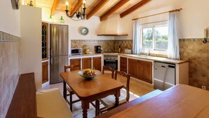 A kitchen with wooden cabinets, a dining table, and a chandelier.