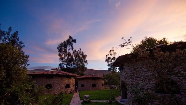 A stone building with a tiled roof, surrounded by greenery and a pathway. - VACATION HOUSE 1 ILLA WASI, CUZCO (Urubamba)