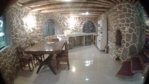 A stone-walled room with a wooden table and chairs, a built-in stove, and a window. - VACATION HOUSE 1 ILLA WASI, CUZCO (Urubamba)