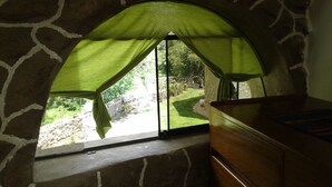 A room with a stone wall, a wooden bench, and a window with a green curtain. - VACATION HOUSE 1 ILLA WASI, CUZCO (Urubamba)