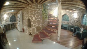 A stone-walled interior with a wooden staircase, seating area, and a kitchen with wine glasses. - VACATION HOUSE 1 ILLA WASI, CUZCO (Urubamba)