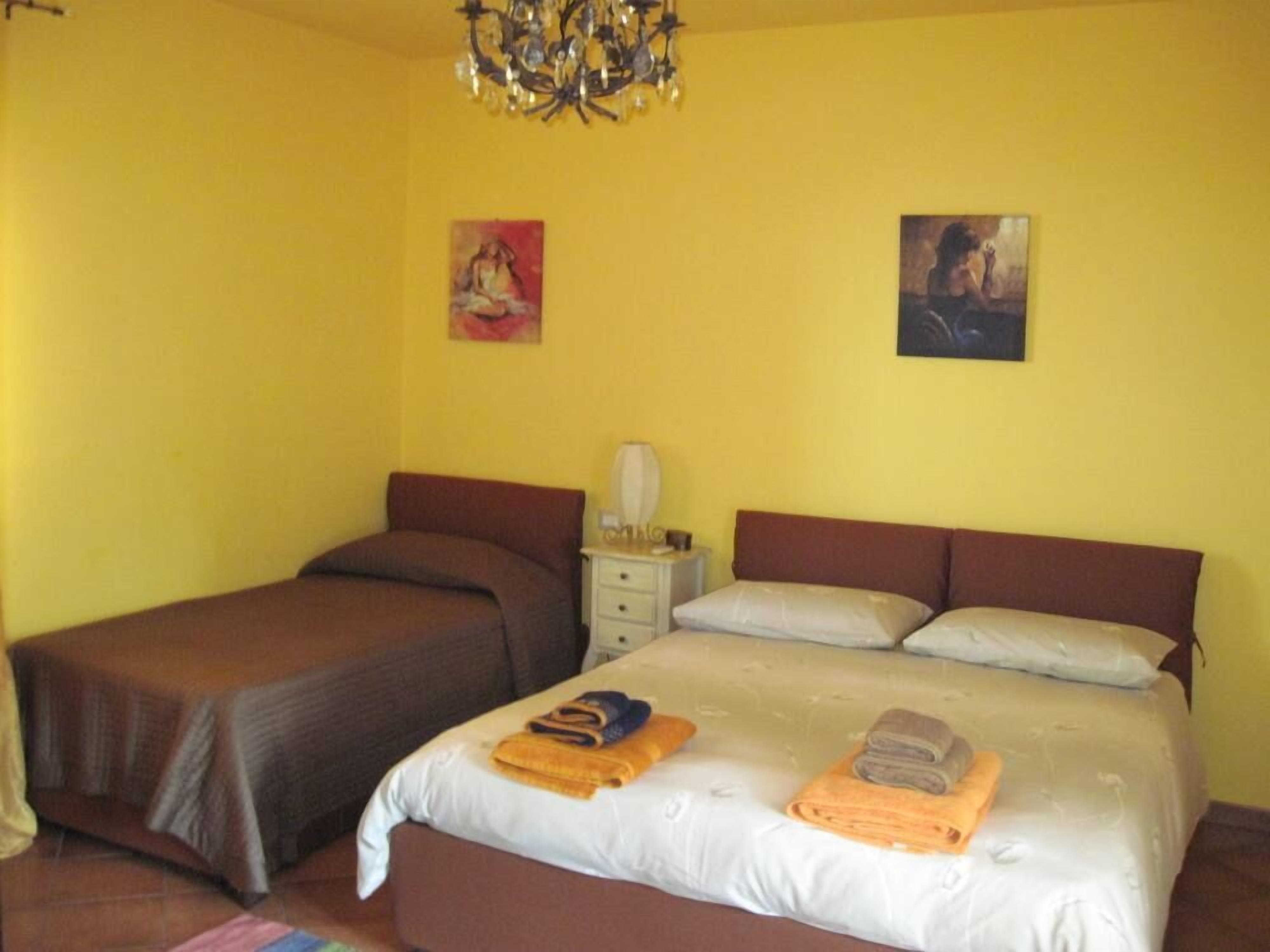 A room with two beds, a nightstand, and a chandelier.