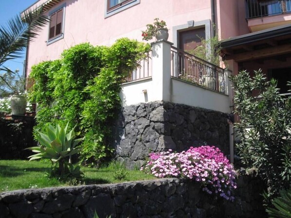 A pink building with a stone wall and a balcony.