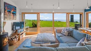 Amplia sala de estar con un ventanal, chimenea y televisor.