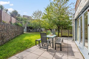 Un patio con mesa y sillas, un muro de piedra y un árbol.