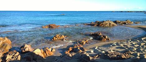 Une plage rocheuse avec une eau claire et une zone de sable.