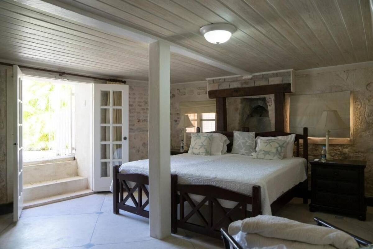Un dormitorio con cama, mesita de noche, lámpara y ventana.