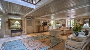 A spacious living room with a large map rug, a white sofa, a white armchair, and a coffee table. - We Stay Well Sanctuary Barbados - Wellness in Paradise (Bridgetown)