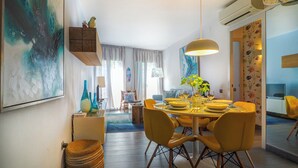 Un espace repas moderne avec une table ronde, des chaises jaunes et un luminaire suspendu.