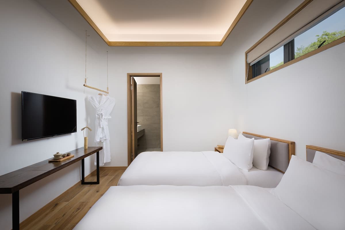 Une chambre d’hôtel avec deux lits, une télévision, une table de chevet et une fenêtre.