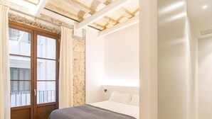 Une chambre à coucher avec un lit, une fenêtre avec des rideaux et un mur en pierre.