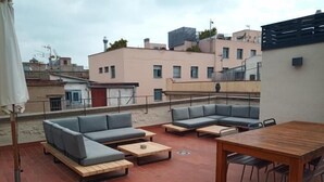 Un espace extérieur aménagé en terrasse, avec une table en bois et deux canapés, une table ronde et une chaise.