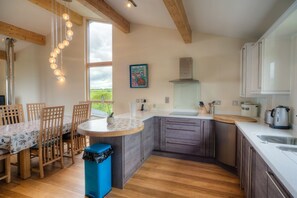 A modern kitchen with wooden flooring, a central island, and a dining area with wooden chairs.