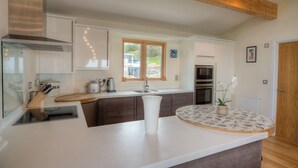 Una cocina moderna con una isla central, vigas de madera y vistas al exterior.