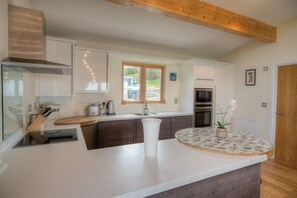 A modern kitchen with a central island, wooden beams, and a view of the outdoors.