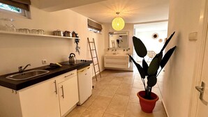 A modern kitchen with a sink, kettle, and potted plant.