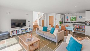A modern living room with a flat-screen TV, a sofa set, a coffee table, and a bookshelf.
