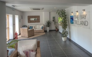 A spacious lobby with a sofa, a chair, and a potted plant.