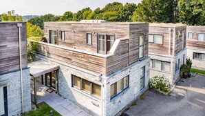 Een modern meerlaags woongebouw met een stenen gevel en houten bovenverdiepingen.