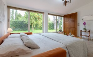 Une chambre à coucher avec un grand lit, deux fenêtres, une armoire en bois et un lustre.