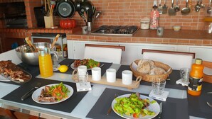 A dining table set with various dishes, a bottle of orange juice, and a basket of bread. - Family house with pool by the beach (Atouguia da Baleia)