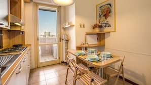 Una cocina con estufa a gas, armarios de madera, una mesa de comedor con sillas y vistas a través de un ventanal.