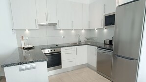 A modern kitchen with white cabinets, stainless steel appliances, and a granite countertop. - Idaira III new spacious apartment with private garage and beach walking distance (Los Cristianos)