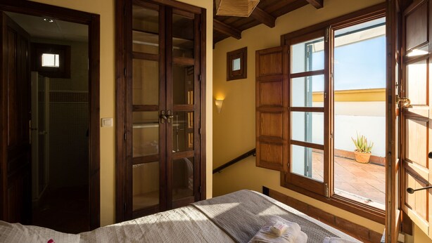 Ein Zimmer mit einem Bett, Holztüren, einem Fenster mit Aussicht und einem Deckenventilator.
