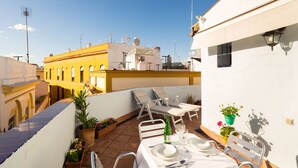 Eine Dachterrasse mit Esstisch, Lounge-Sesseln und Topfpflanzen.