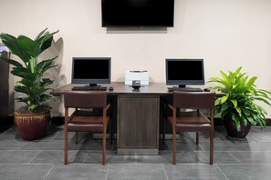 Uma sala de conferências com dois monitores, uma impressora e duas cadeiras.